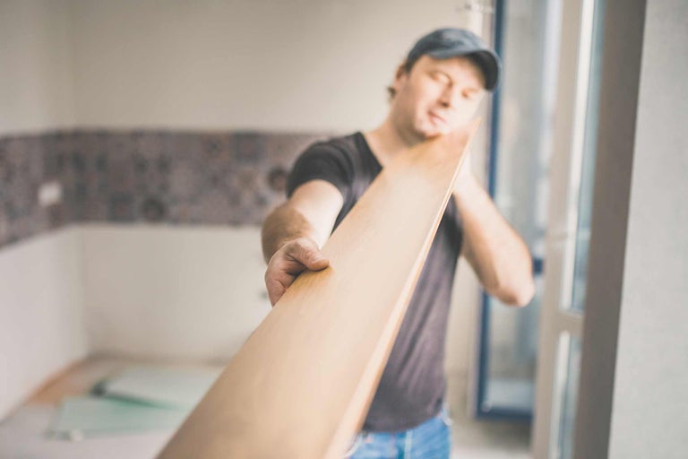 Un bărbat ține un panou care este folosit pentru instalarea laminatului