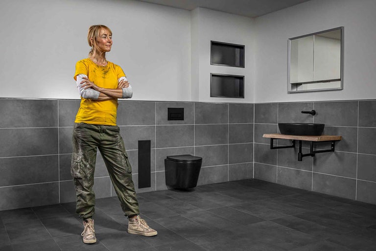 Baie modernă cu gresie, toaletă, chiuvetă și instalator