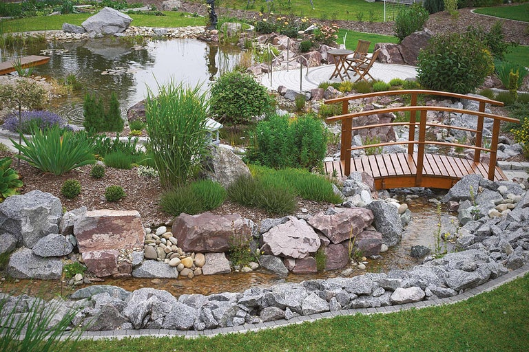 Lac de grădină cu pod de lemn, pietre și vegetație