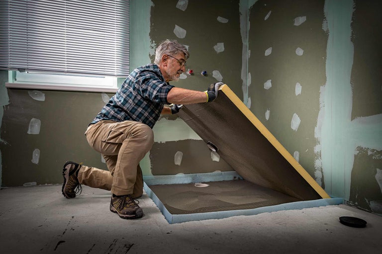 Meșter instalează un element de duș în baie. Elementul de duș este realizat din spumă poliuretanică rigidă și are o tehnologie de scurgere integrată.