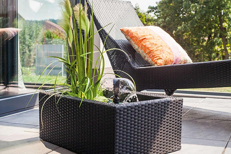 Grădină cu fântână arteziană, plante și șezlong