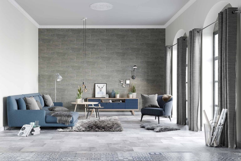 Cameră de zi cu canapea albastră, fotoliu, perdele gri și perete cu model