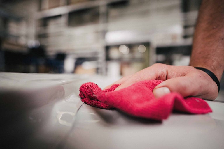 Mână cu cârpă de curățare roșie ștergând o suprafață