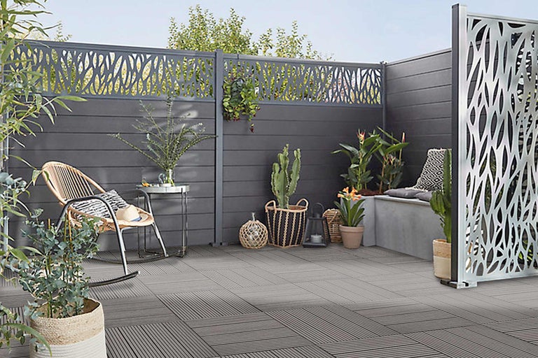 Spațiu exterior amenajat cu paravan de intimitate, mobilier de grădină și plăci de podea