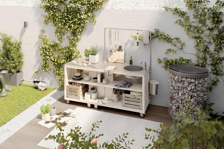 Bucătărie de exterior cu chiuvetă, grătar și unelte de grădină într-un spațiu exterior verde.