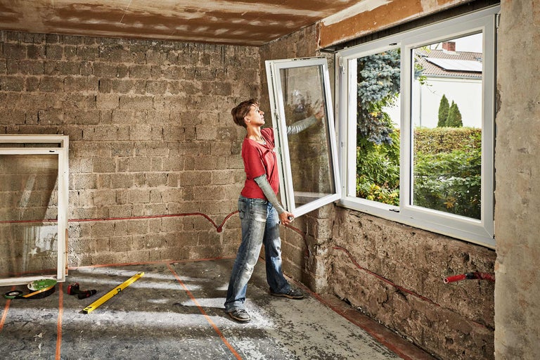 Femeie montează o fereastră într-o cameră.