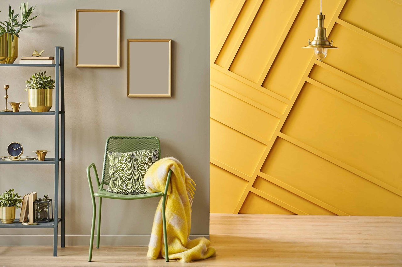 Cameră de zi decorativă cu rafturi, scaun, pernă, pătură și decor de perete