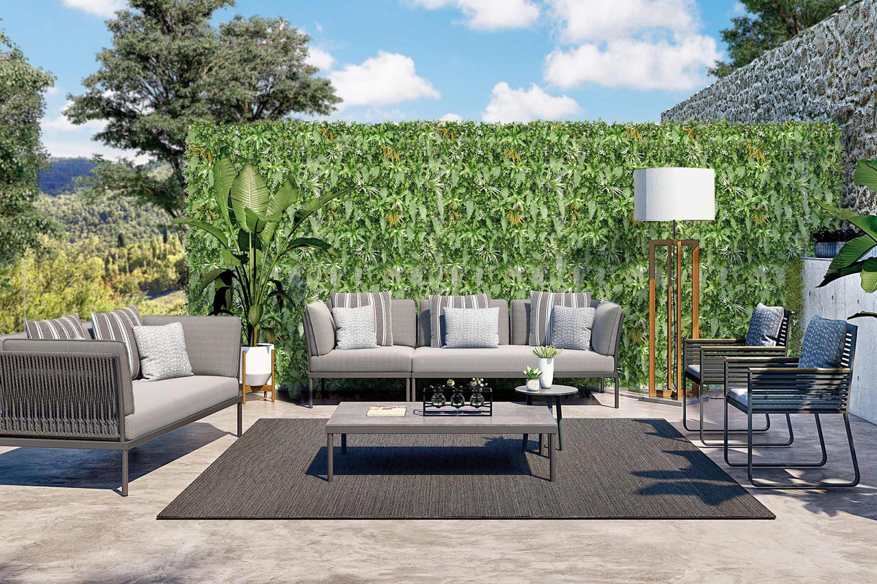 Terasa cu canapea, fotolii, masă, covor și perete cu plante