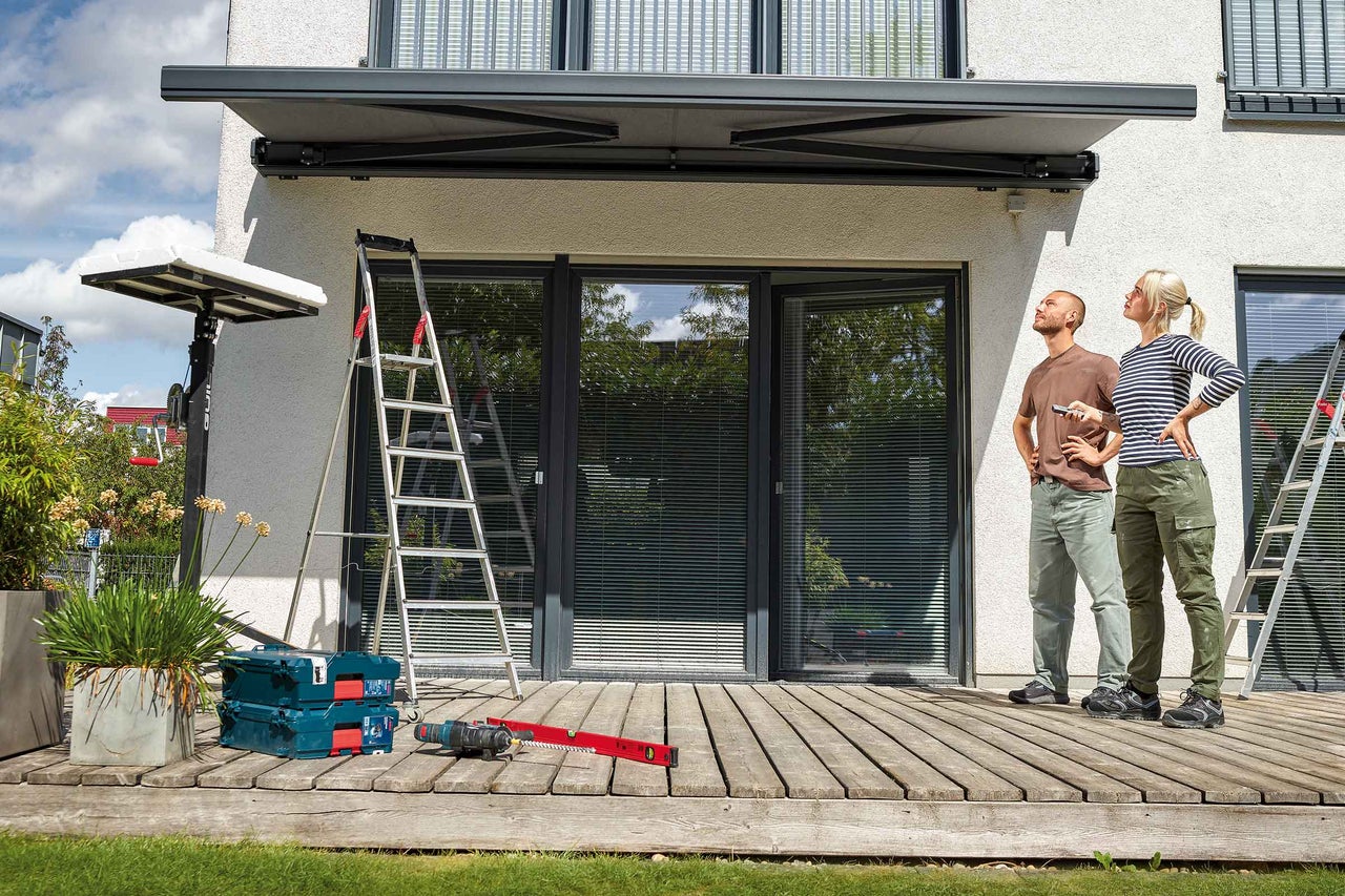 Terasa cu podea din lemn, masă din lemn cu două scaune, bambus și pânză de umbrire