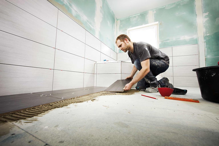 Artizan care montează gresie în baie