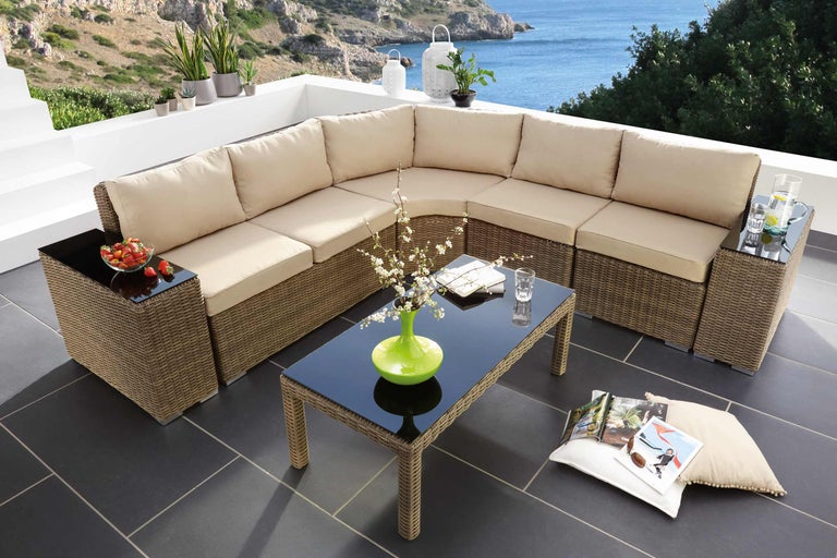 Grup mare de lounge de exterior cu masă pe o terasă cu vedere la mare.