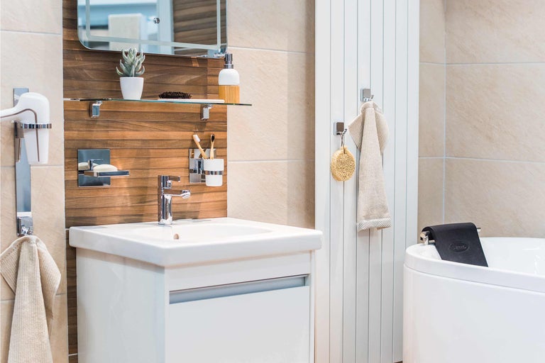 Baie luminoasă cu lavoar, oglindă, radiator pentru prosoape și cadă.