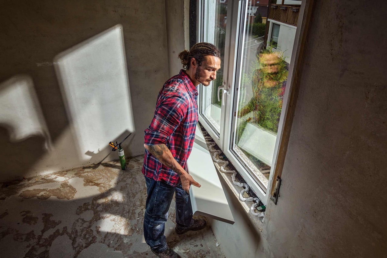 Bărbat montează o glafă de fereastră într-o clădire în construcție.