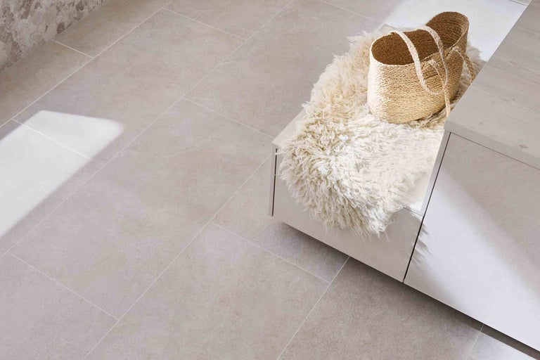 Instalare de plăci ceramice lângă o piesă de mobilier albă cu o piele de oaie și un coș