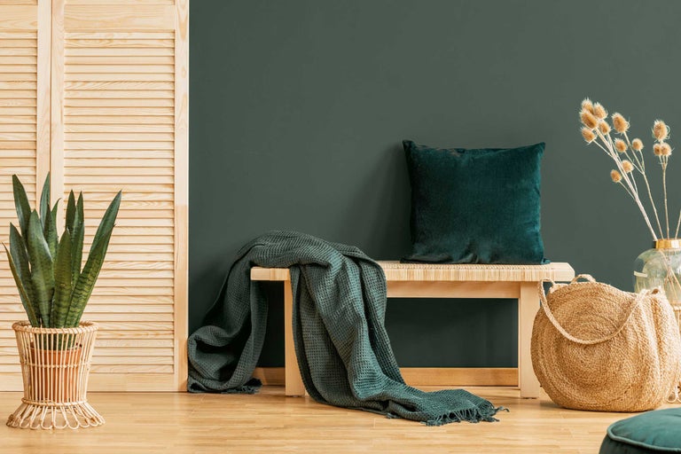 Atmosferă decorativă de locuit cu bancă, pernă, pătură, plantă și coș împletit