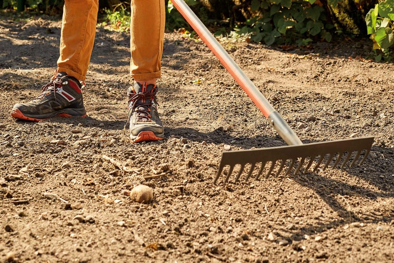 Persoană cu greblă pe pământ