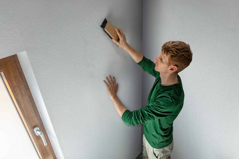 Bărbat structurează peretele cu o perie