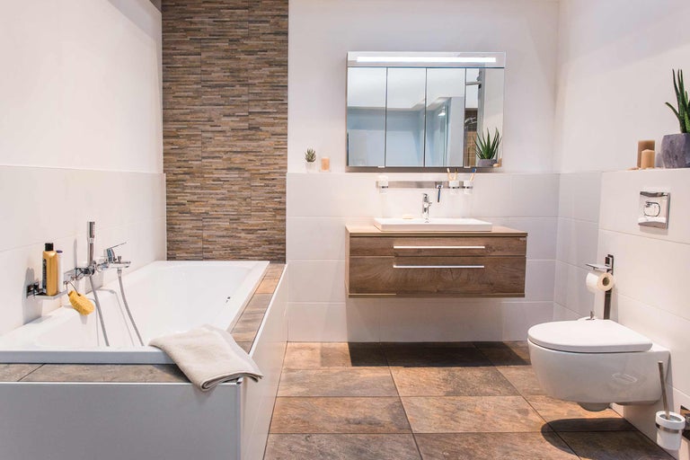 Baie modernă cu cadă, chiuvetă, dulap cu oglindă și toaletă pentru o atmosferă luminoasă și prietenoasă