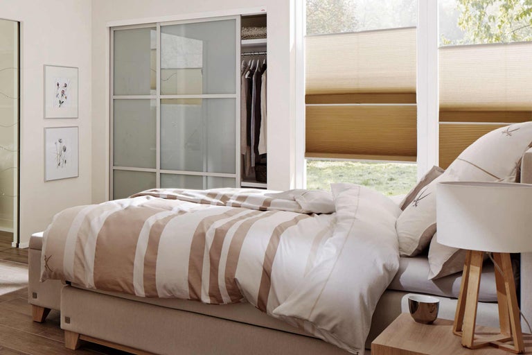 Dormitor cu pat matrimonial, dulap cu uși glisante și jaluzele plisate