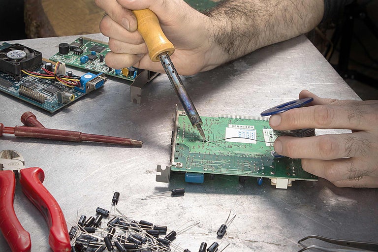 Lipirea unei plăci electronice cu ciocanul de lipit și cositor pe o masă de lucru.