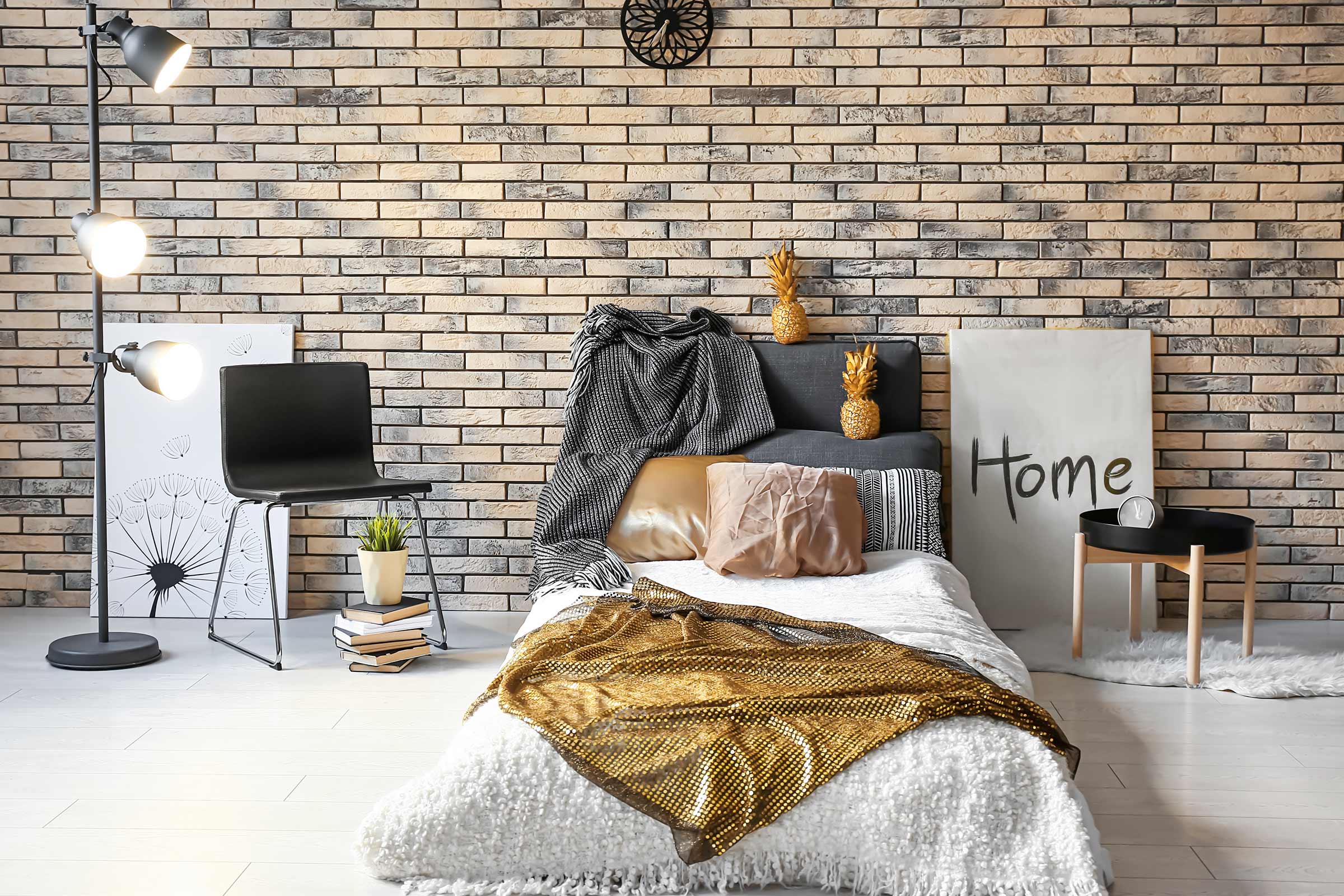 Dormitor decorativ cu pat, scaun, lampadar și perete de cărămidă