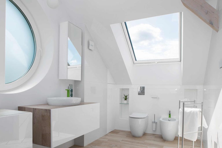 Baie luminoasă cu fereastră de mansardă, fereastră rotundă, chiuvetă, toaletă și bideu