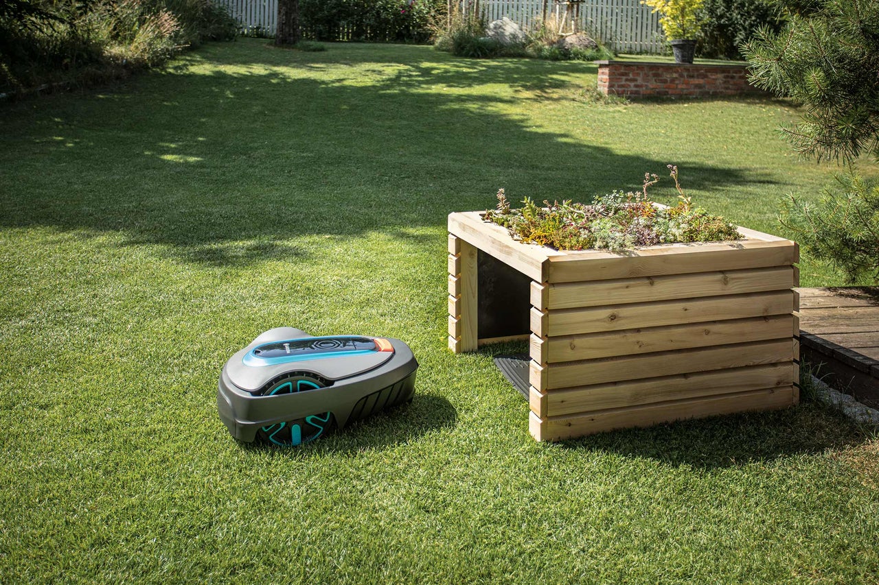 Scenă de grădină cu robot de tuns iarba și masă de plantare din lemn.