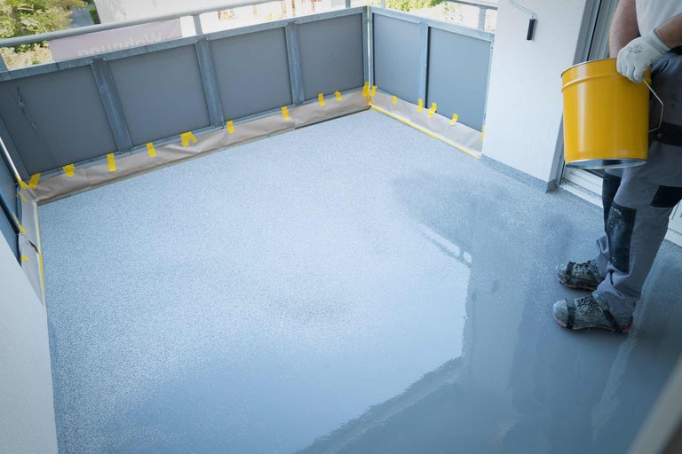 Acoperire podea balcon cu găleată galbenă de vopsea și bandă de mascare.