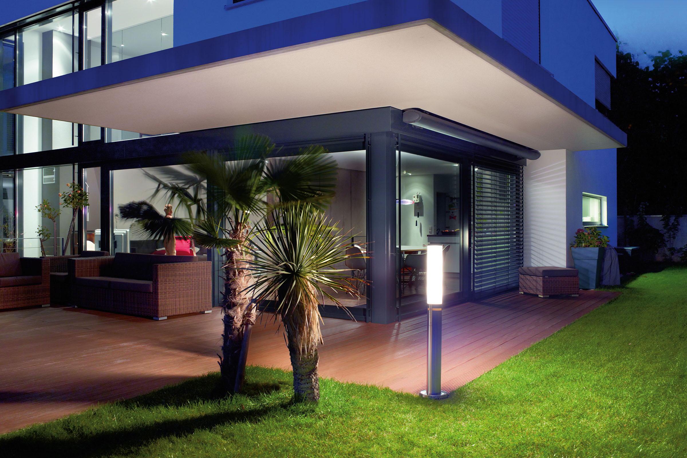 Terasa modernă cu mobilier de ședere, scânduri de terasă și corp de iluminat exterior în grădină