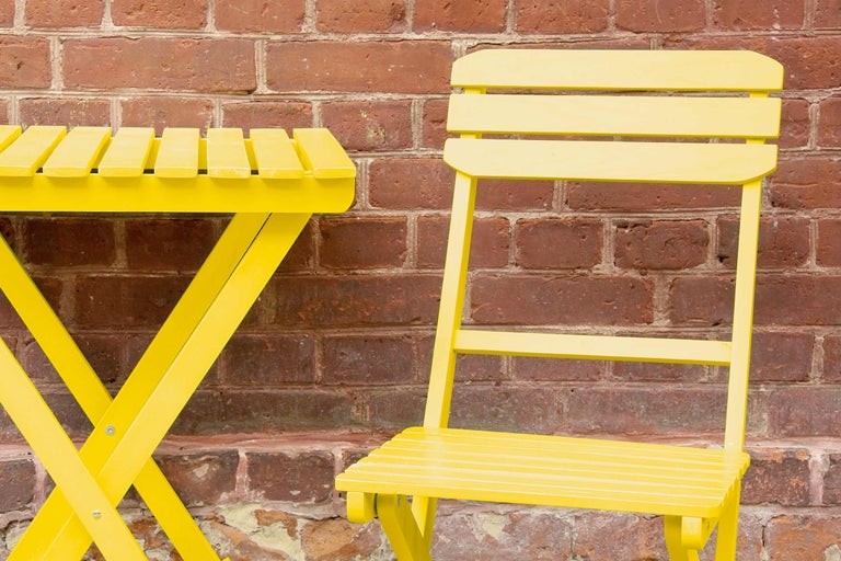 Măsuță pliabilă și scaun galben în fața unui perete de cărămidă