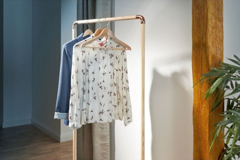 Suport de haine din lemn cu haine atârnate în cameră