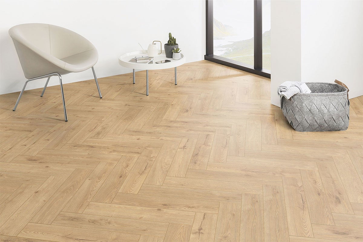 Cameră luminoasă cu parchet în spic, fotoliu, masă și coș