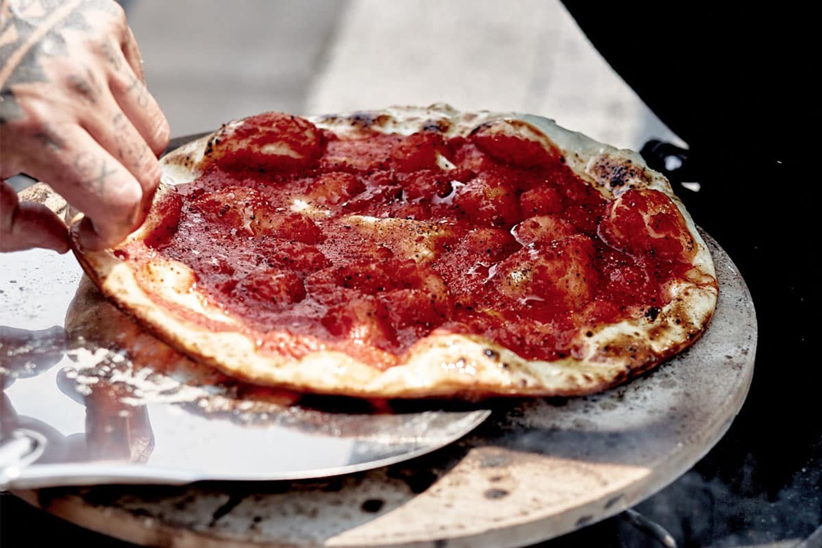 O pizza cu sos de roșii servită pe o piatră pentru pizza.