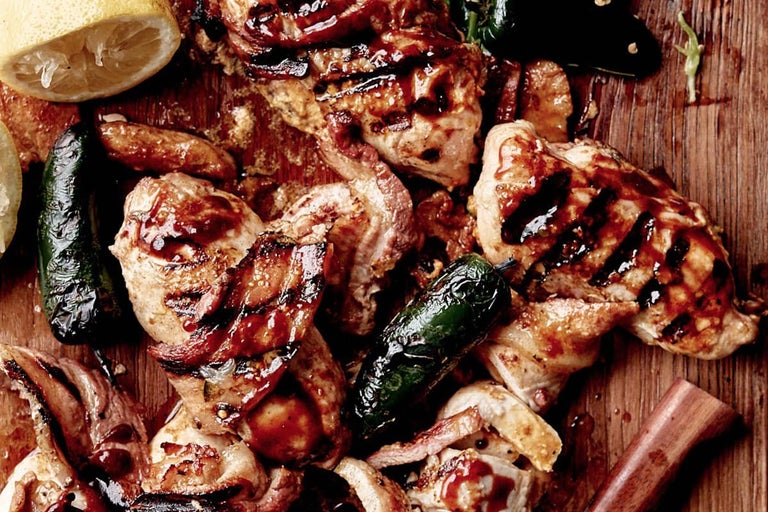 Prim-plan cu pui la grătar cu jalapeños și lămâie pe o scândură de lemn