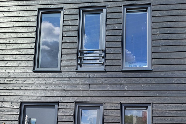 Fațadă cu placare din lemn și mai multe ferestre