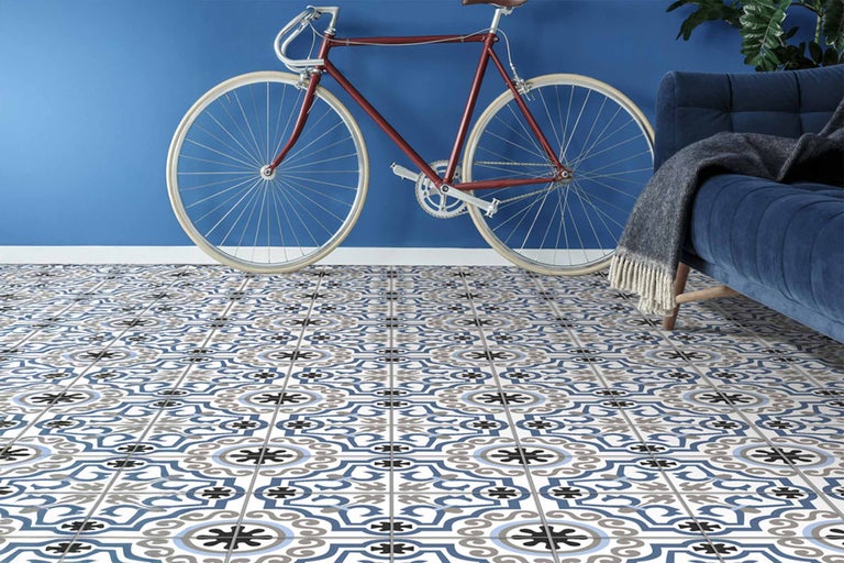Vedere a camerei cu plăci decorative de podea, bicicletă roșie și canapea albastră.