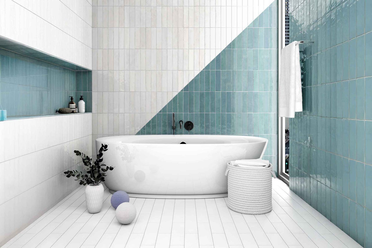 Baie modernă cu faianță albă și verde, cadă independentă și elemente decorative.