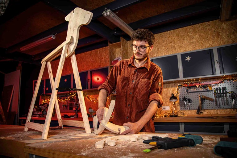 Bărbat construind un cal balansoar din lemn în atelier