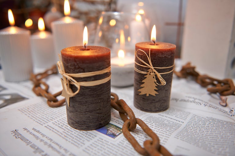 Lumânări decorative cu ornamente și lanț rustic pe un ziar