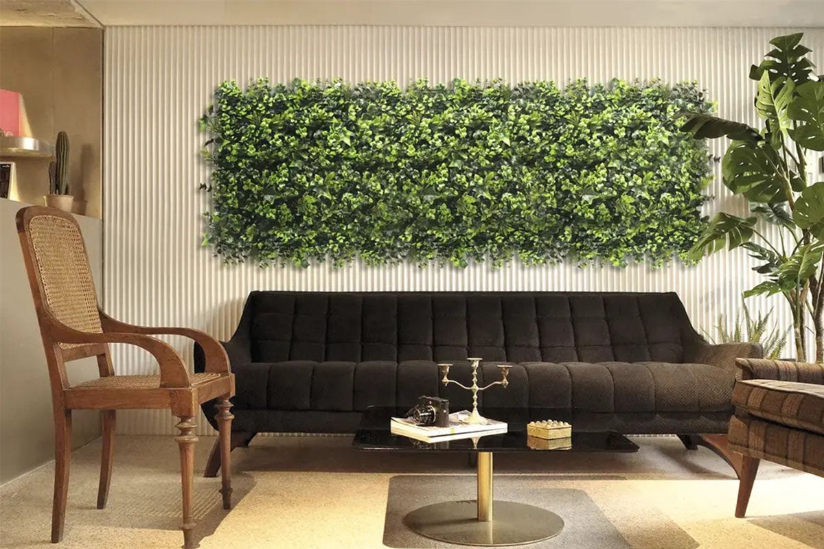 Sufragerie cu perete verde de plante deasupra unei canapele.