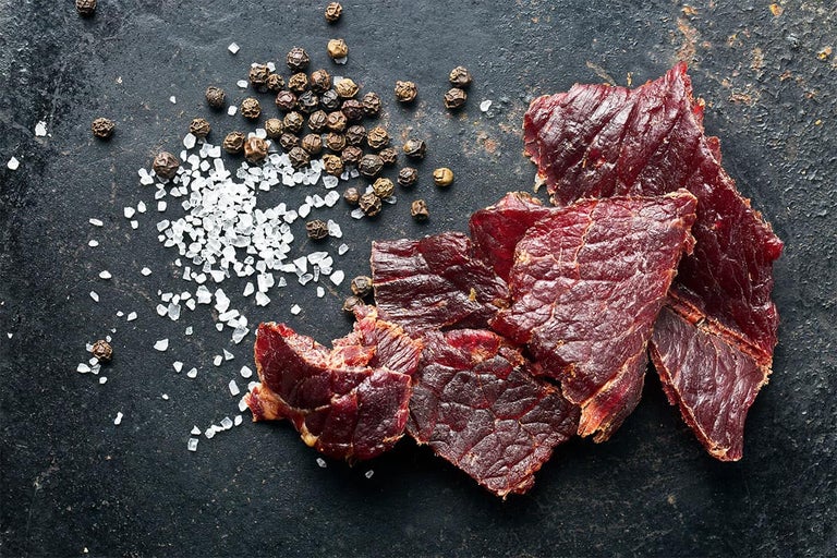 Prim-plan cu carne uscată cu sare și boabe de piper