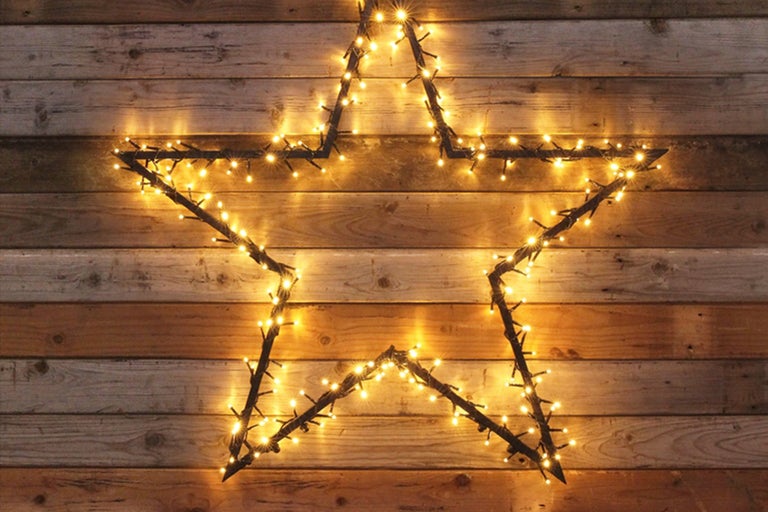 Stea decorativă cu lumini în fața unui perete de lemn