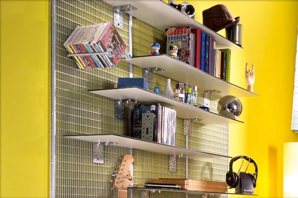Sistem de rafturi cu polițe pe un perete metalic tip grilaj, decorat cu cărți, muzică și căști