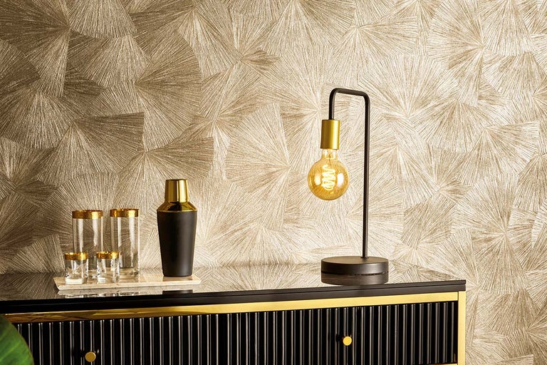 Amenajare interioară decorativă cu tapet cu model, pahare de cocktail, shaker și lampă pe o comodă