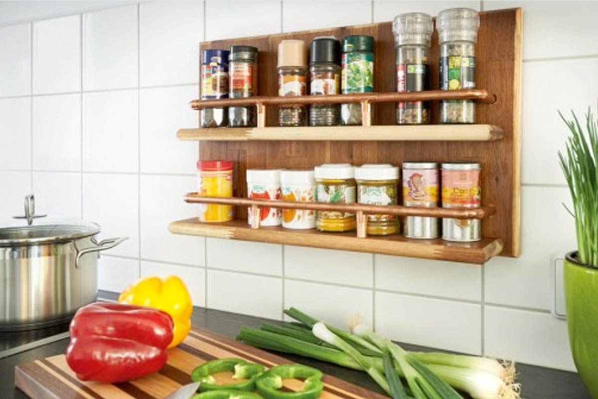 Raft din lemn pentru condimente cu borcane pentru condimente pe un perete cu faianță într-o bucătărie