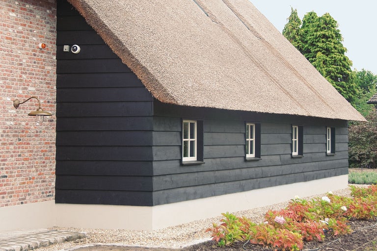 Clădire cu acoperiș din stuf, fațadă din lemn, cameră de supraveghere și iluminat exterior