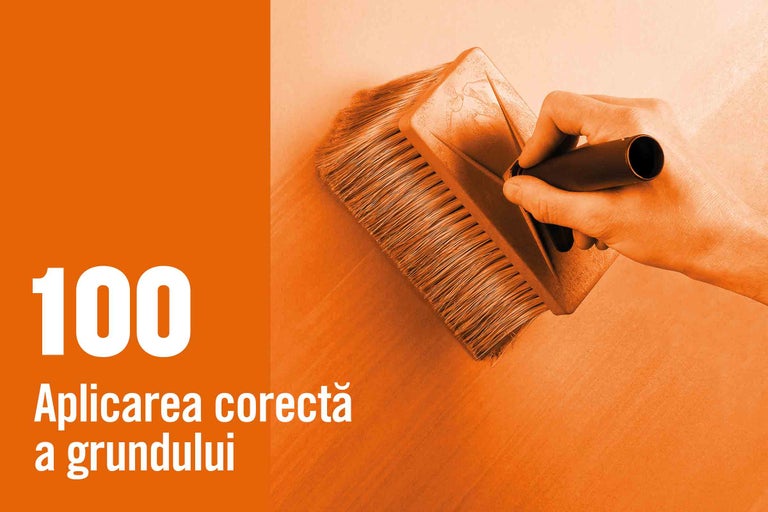 Mână amorsând un perete cu o pensulă plată.