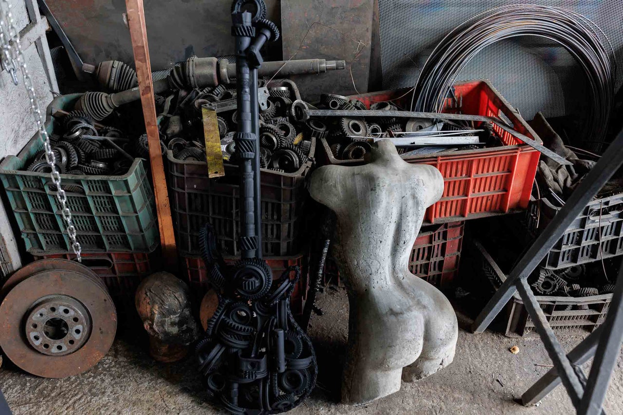 Scenă cu fier vechi, o chitară făcută din roți dințate și o sculptură de tors feminin
