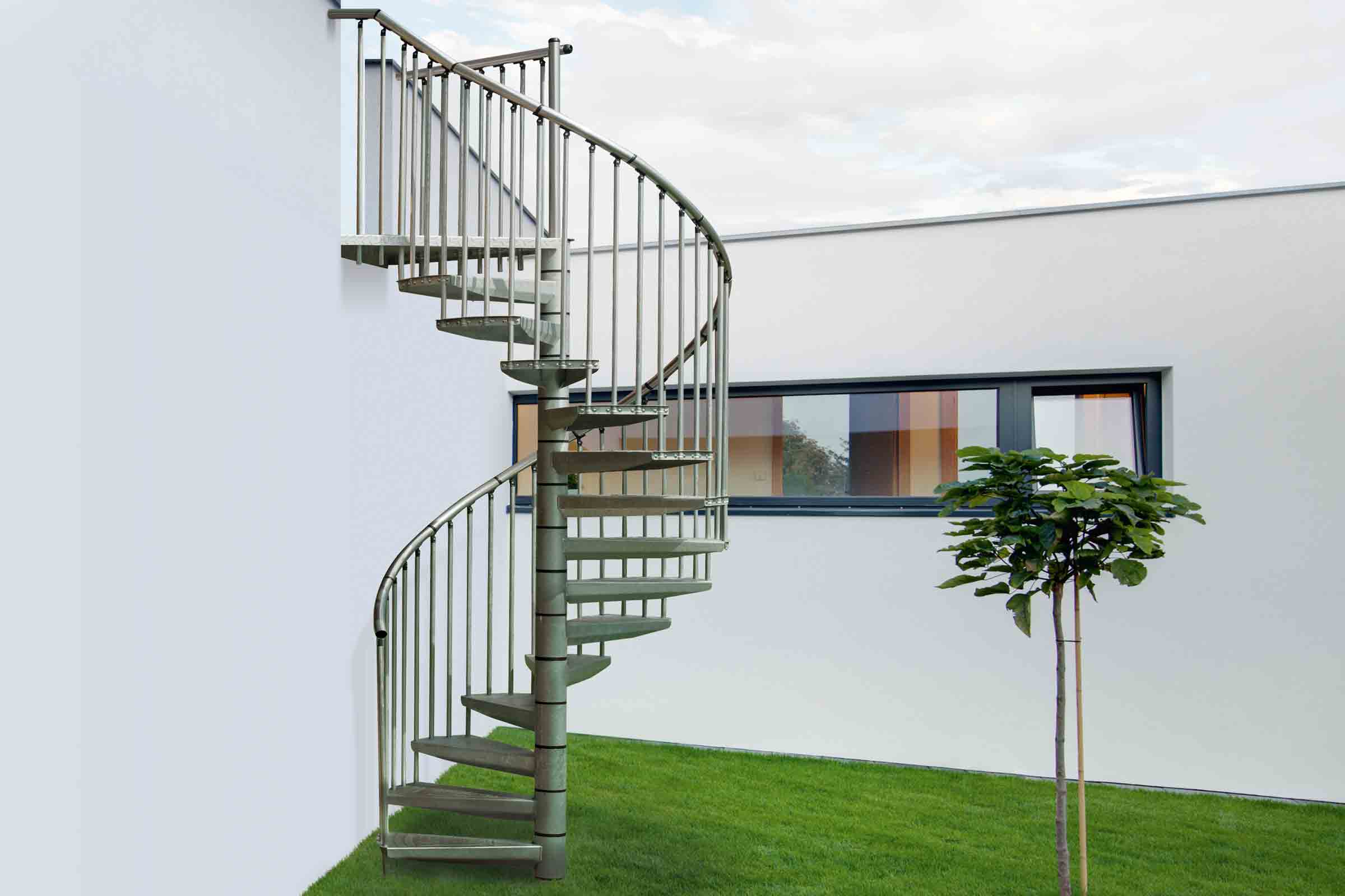 Scară spirală metalică exterioară cu balustradă în fața unei case albe