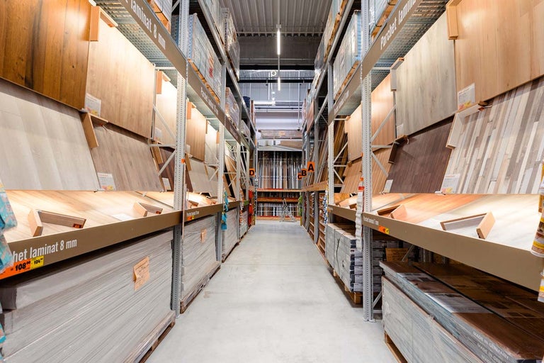 Alee într-un magazin de bricolaj cu rafturi pline cu laminate și parchet